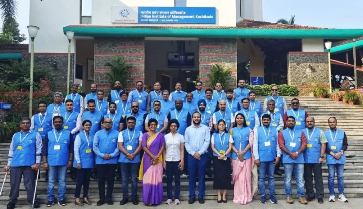 A large cohort in matching jackets standing outside an IIM Kozhikode building