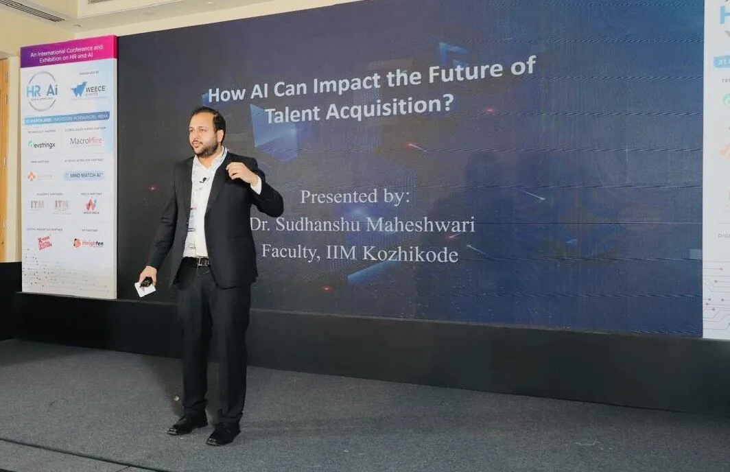 Speaking on stage beside a slide reading How AI Can Impact the Future of Talent Acquisition
