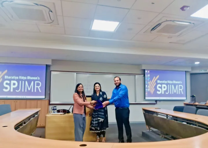 A memento being presented at the front of an SPJIMR classroom
