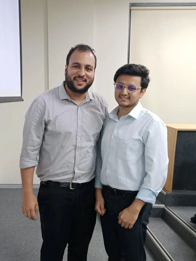 Two people standing in front of a projection screen in a classroom