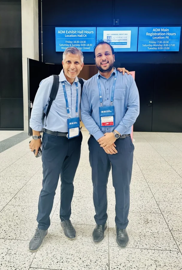 Two delegates standing in front of an Academy of Management registration screen