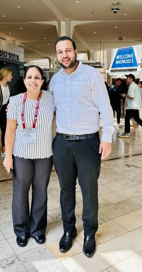 Two conference delegates standing near a welcome sign in a convention centre