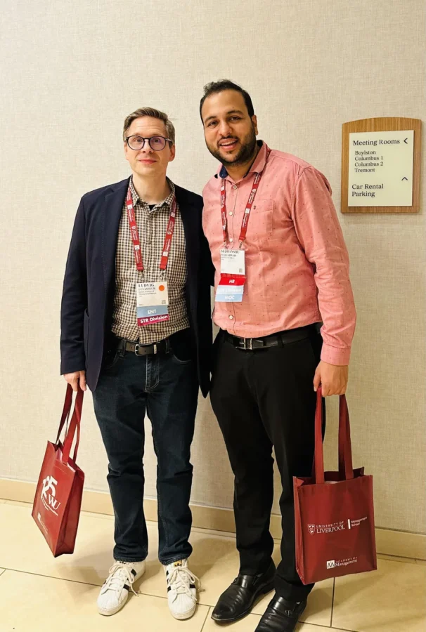 Two delegates carrying conference tote bags outside a session room