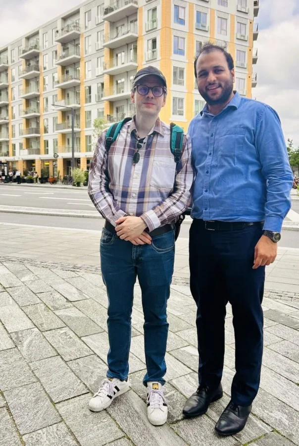 Two people standing on a street beside a modern building