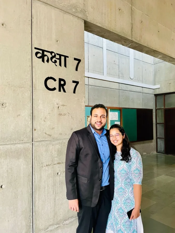 Two people standing beside a classroom sign reading CR 7