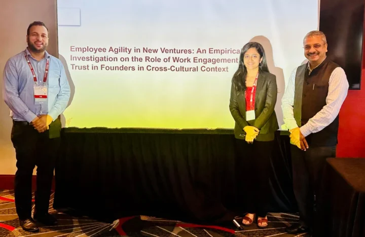 Three presenters standing beside a projected slide titled Employee Agility in New Ventures at a conference session