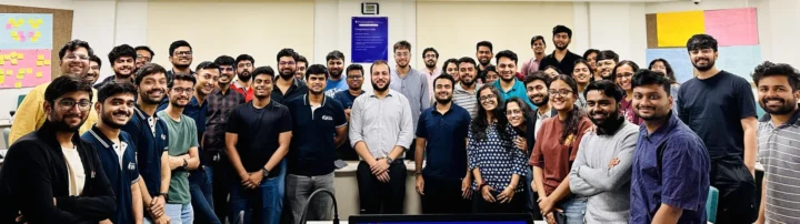A large cohort standing together in a classroom