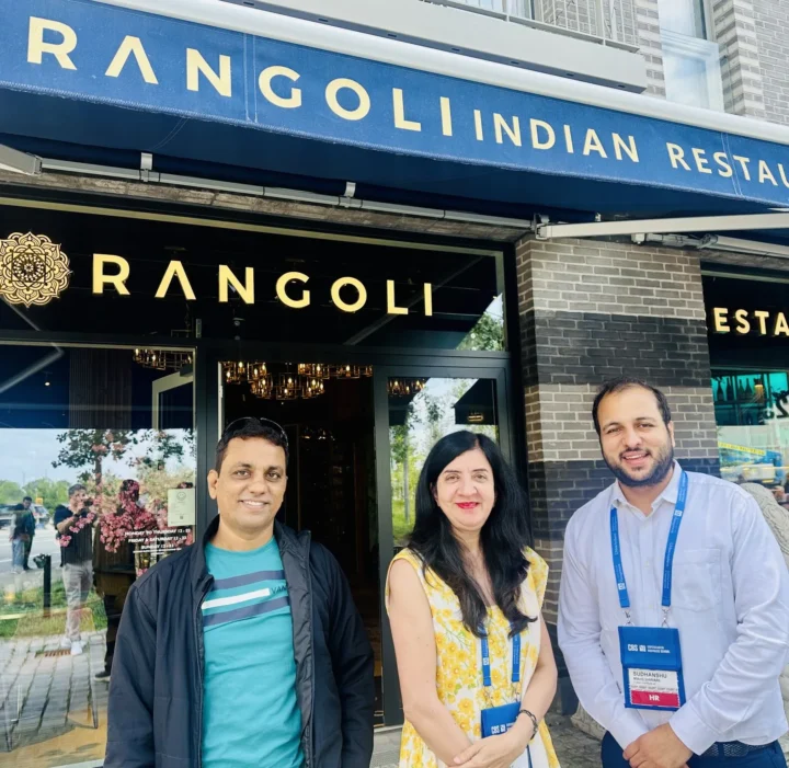 Three people standing outside an Indian restaurant